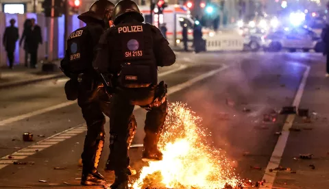epa11800684 Riot police officers attempt to put out the flames from an exploded pyrotechnic during the New Year's celebrations in Berlin, Germany, 01 January 2025. EPA/FILIP SINGER