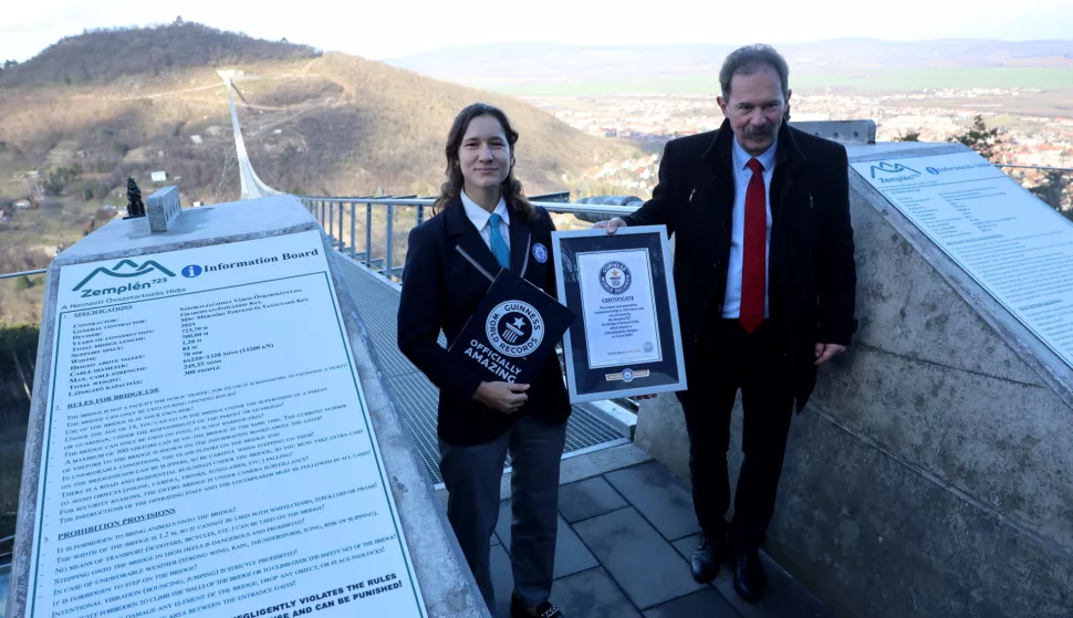 epa11861281 Mayor Peter Szamosvolgyi (R) and official GWR adjudicator Anouk de Timary pose with the Guinness World Records certificate proving the Bridge of National Unity is the longest-span pedestrian suspension bridge of the world, at the foot of the bridge in Satoraljaujhely, Hungary, 29 January 2025. The 723m long bridge was inaugurated on 04 June 2024. EPA/JANOS VAJDA HUNGARY OUT