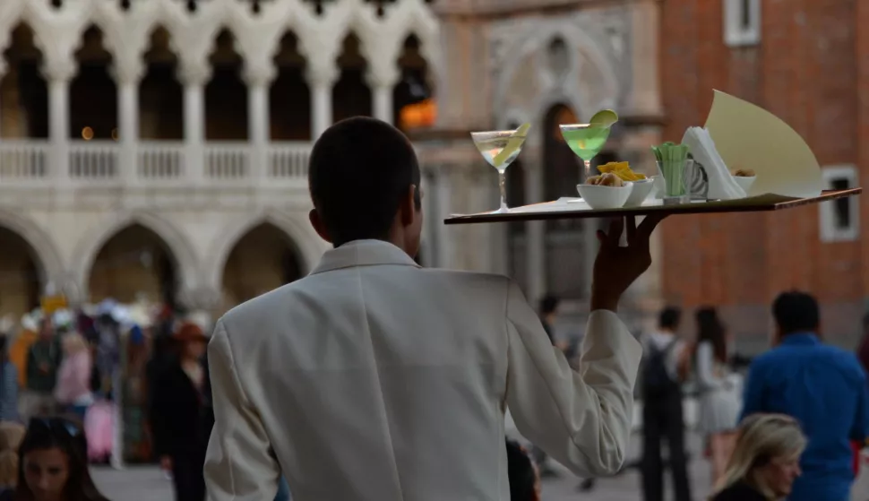 epa07046700 The waiter of a historic cafAŠ in Piazza San Marco serves drinks in Venice, Italy, 25 September 2018.Venice is mulling a ban on carrying alcoholic drinks in the streets after seven p.m., or even having bottles of drink in your shopping bag. The proposal, the umpteenth aimed at protecting the lagoon city's 'decorum', is before the city council. EPA/Andrea Merola
