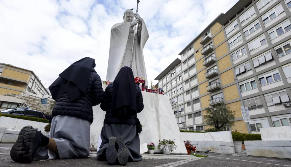 epa11910230 Two nuns pray under the statue of Pope John Paul II, at the Gemelli polyclinic, where Pope Francis is hospitalized in Rome, Italy, 20 February 2025. Pope Francis is continuing to do some work while he is being treated at Rome's Gemelli hospital for bronchitis and double pneumonia, Vatican sources said on Thursday. Pope Francis was hospitalized on 14 February due to a respiratory tract infection. EPA/MASSIMO PERCOSSI