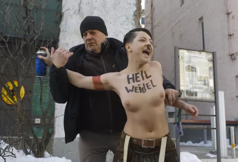 epa11917665 Security intervene as an activist from Ukraine's feminist group FEMEN impersonates Adolf Hitler while protesting against the Alternative for Germany (AfD) party and its leader Alice Weidel, on the day Germany holds its federal elections, outside the German embassy in Kyiv, Ukraine, 23 February 2025. The group accuses the German right-wing party AfD of having ties with Russia. EPA/SERGEY DOLZHENKO