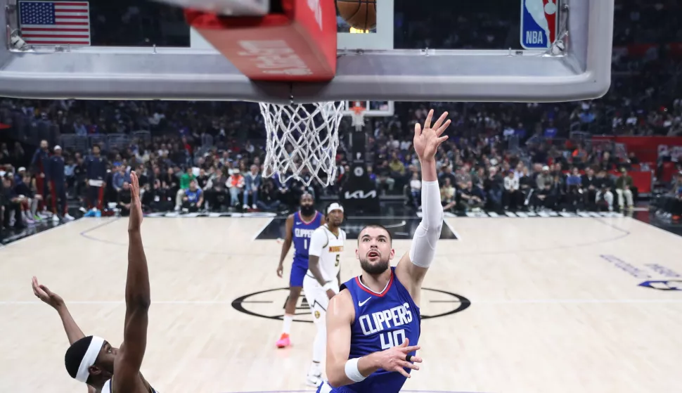 epa10998557 LA Clippers center Ivica Zubac (R) drives to the basket with the ball while being guarded by Denver Nuggets forward Justin Holiday (L) during the first quarter of the NBA basketball game between the Los Angeles Clippers and the Denver Nuggets at Crypto.com Arena in Los Angeles, California, USA, 27 November 2023. EPA/CAROLINE BREHMAN SHUTTERSTOCK OUT