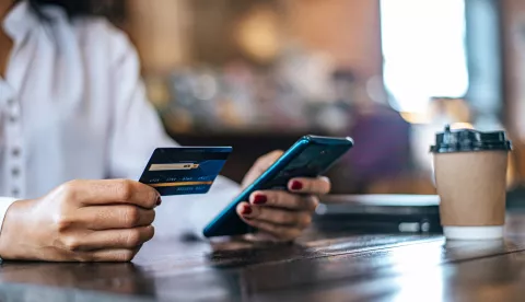 Pay for goods by credit card through a smartphone in a coffee shop.