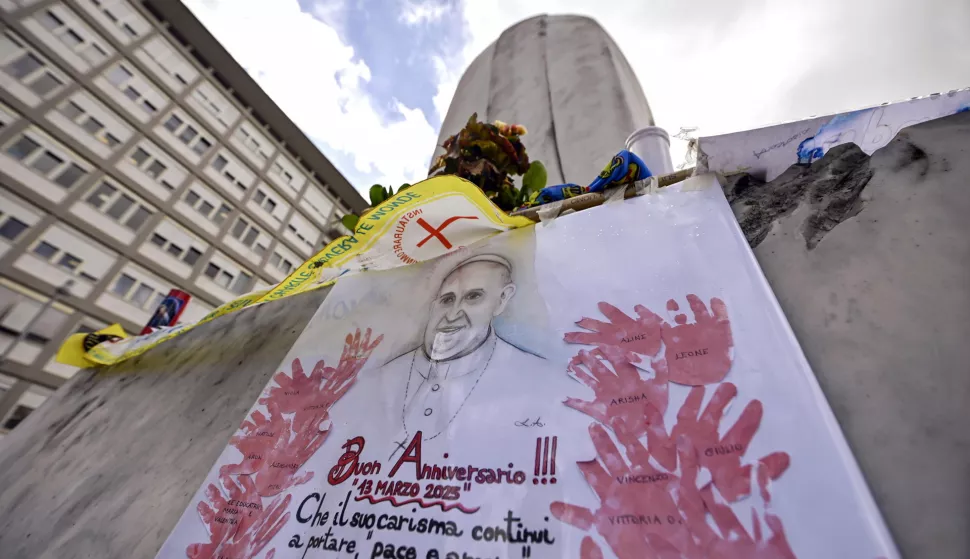 epa11960421 A banner celebrating the 12th anniversary of Pope Francis' pontificate is seen at the statue of John Paul II at the entrance of Gemelli Hospital where Pope Francis is still hospitalized, Rome, Italy, 13 March 2025. EPA/RICCARDO ANTIMIANI