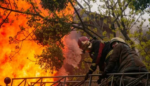 Harkiv, Ukrajina, 17.04.2022. - Vatrogasci gase poЕѕar na jednoj od ulica u Harkivu. Od posljedica ruske raketne paljbe u centru Harkiva pet je osoba poginulo, a 13 ozlijeД'eno. Vatrogasci su ugasili preko petnaest poЕѕara. foto (aldg) PAP/Mykola Kalyeniak