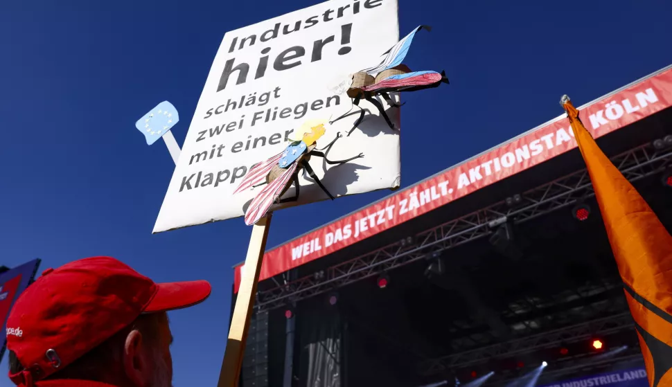 epa11965685 A participant holds a sign reading 'Industry here, kills two birds with one swatter' during a rally organized by the IG Metall trade union in Cologne, Germany, 15 March 2025. IG Metall has called for a nationwide day of protest, urging the incoming federal government to implement measures that would improve conditions for the industry. EPA/CHRISTOPHER NEUNDORF