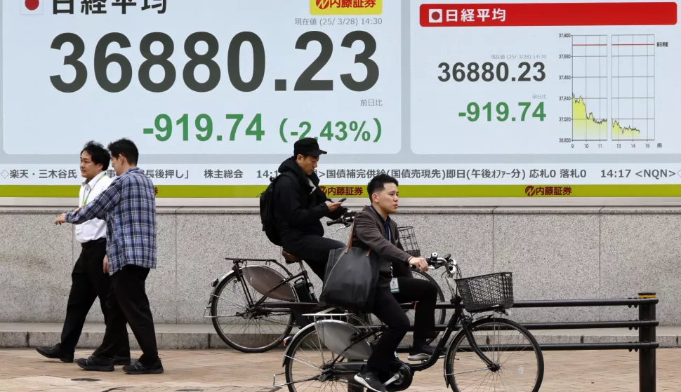epa11994038 Pedestrians walk past a stock market indicator board in Tokyo, Japan, 28 March 2025. The Nikkei Stock Average closed at 37,120.33 yen, down 679.64 points from the previous day on the Tokyo stock market after briefly losing over 900 points, following concerns over US auto tariffs on Japanese automakers. EPA/FRANCK ROBICHON
