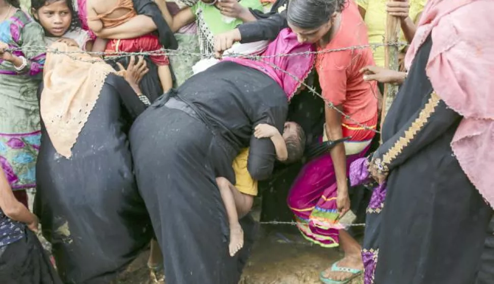 epa06256911 A Rohingya woman tries to cross a barb wire fence with her son to get into the queue to get relief goods in Ukhiya, Coxsbazar, Bangladesh, 10 October 2017. According to the United Nations High Commissioner for Refugees (UNHCR), more than 525 thousand Rohingya refugees have fled Myanmar from violence over the last few weeks with most of them trying to reach Bangladesh. International organizations have reported claims of human rights violations and summary executions allegedly carried out by the Myanmar army. Minister for the Office of the State Counsellor of Myanmar Kyaw Tint Swe visited Bangladesh and agreed to take back the Rohingyas after mutual understanding with the Bangladesh government. EPA/ABIR ABDULLAH