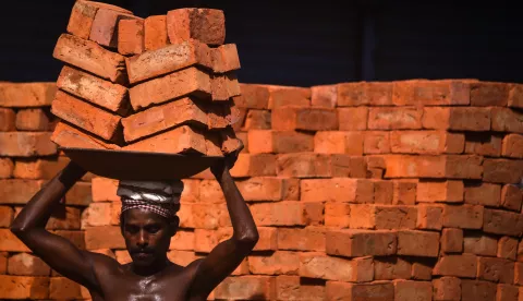 epa10727001 An Indian laborer carries bricks on his head at an under-construction commercial complex, in Chennai, India, 05 July 2023. EPA/IDREES MOHAMMED