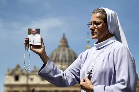 epa12044119 A nun carries a cross and a picture of Pope Francis as she prays in St. Peter's Square following the death of Pope Francis, Vatican City, 21 April 2025. Pope Francis died on 21 April 2025 at the age of 88, according to the Holy See. Born Jorge Mario Bergoglio in Buenos Aires, Argentina, on 17 December 1936, he was appointed leader of the Catholic Church on 13 March 2013, succeeding Pontiff Emeritus Benedict XVI. EPA/ANGELO CARCONI