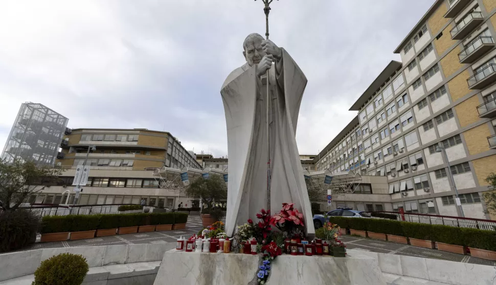 epa11898601 Flowers and candles lay at the foot of a statue of Pope St. John Paul II outside the Gemelli University Hospital in Rome, Italy, 15 February 2025, where Pope Francis was hospitalized the previous day over a respiratory tract infection. EPA/MASSIMO PERCOSSI