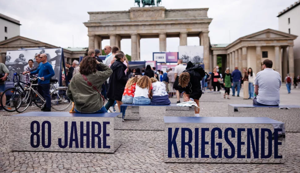 epa12070855 Onlookers sit on blocks that read '80 years - end of war' in front of the Brandenburg Gate in Berlin, Germany, 03 May 2025. From 02 till 11 May, photos and information panels are featured as part of the theme week commemorating '80 years since the end of the war - Europe's liberation from National Socialism'. EPA/CLEMENS BILAN