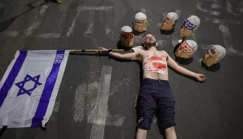 epa12057099 A demonstrators covered in fake blood lies on the street near masks depicting Israeli Prime Minister Benjamin Netanyahu and a national flag as the families of Israeli hostages held by Hamas in Gaza and their supporters take part in a protest calling for the completion of an hostage deal between Israel and Hamas, outside the the Kirya military headquarters in Tel Aviv, Israel, 26 April 2025. According to Israel's military, around 59 Israeli hostages remain in captivity in the Gaza Strip, including the bodies of at least 35 confirmed dead. EPA/ABIR SULTAN