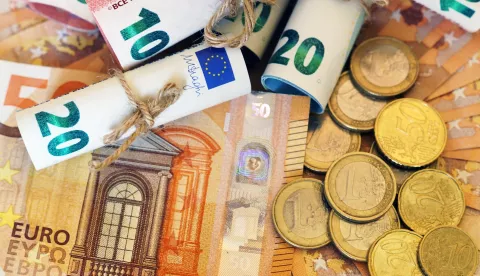 A high angle shot of some rolled banknotes and coins on more banknotesnovac euro digitalni ilustracija freepik