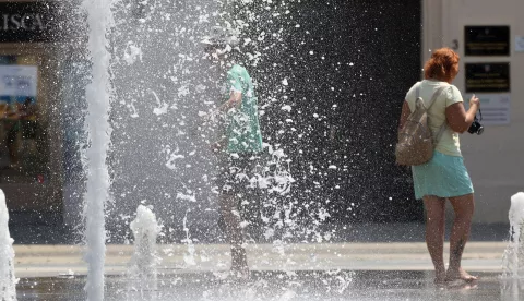 Osijek, 12. 07. 2024, Trg Ante Starcevica, fontana, turisti se osvjezavaju u fontani. Oko 14 sati temperatura u Osijeku je bila 38,8 C tako je pokazivao led displej na obali Drave u Zimskoj luci. Ljudi se snalaze na razne nacine kako bi se zastitili od vrucine i sunca. snimio GOJKO MITIĆ