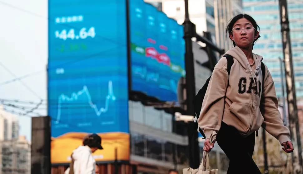 epa12015256 People walk on a street near screens showing stock exchange and economic data in Shanghai, China, 07 April 2025. Hong Kong and Chinese stocks plummeted dramatically on April 7 after Beijing countered US tariffs with its own set of trade levies. The move sent shock waves through financial markets, igniting fears among investors of an expanding trade war that could plunge the global economy into a severe recession. EPA/ALEX PLAVEVSKI