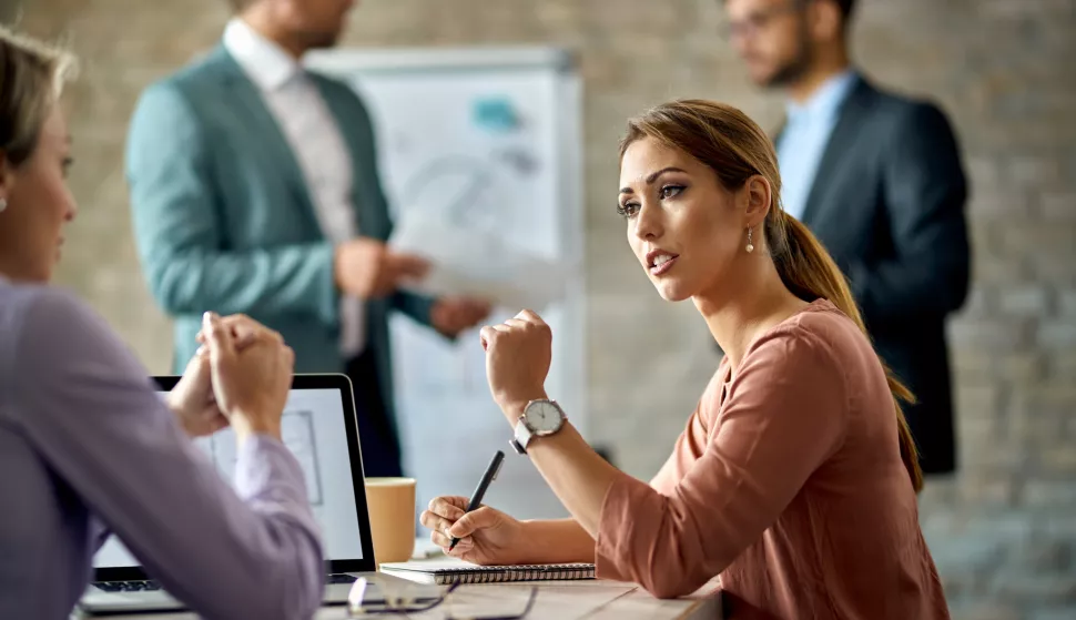 Young businesswoman talking to her female colleague during the meeting in the office.posao gospodarstvo ilustracija aktovka banka kredit pdv bdp gdp pregovori financiranje financije računovostvo freepik