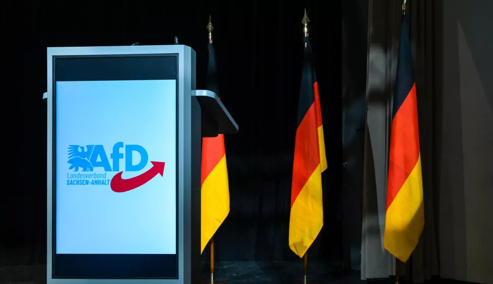 23 May 2025, Saxony-Anhalt, Magdeburg: The AfD logo on the lectern with German flags in the background on the stage in the assembly hall. The candidates for the 2026 state election are being nominated. Photo: Heiko Rebsch/dpa Photo: Heiko Rebsch/DPA