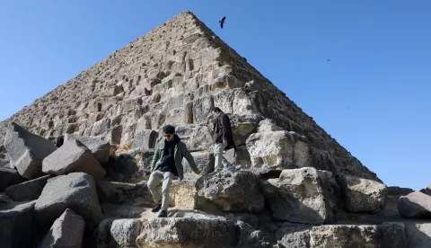 epa11118019 Tourists climb the stones at the base of the Pyramid of Menkaure, at the Giza Pyramids Necropolis, in Giza, Egypt, 01 February 2024. An Egyptian-Japanese joint project led by secretary-general of the Supreme Council of Antiquities Mostafa Waziri is to renovate the Pyramid of Menkaure, which dates back to the 26th century BC and is the smallest of the three main pyramids of the Giza pyramid complex. EPA/KHALED ELFIQI