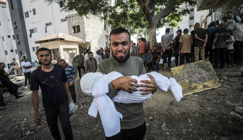 epa12255235 A father carries the shrouded body of his child at the Al-Shifa in Gaza City, 23 July 2025. According to the Palestinian Ministry of Health in Gaza, more than 36 Palestinians were killed, tem of them from the Mushtaha family, following Israeli airstrikes last night and early today. EPA/MOHAMMED SABER