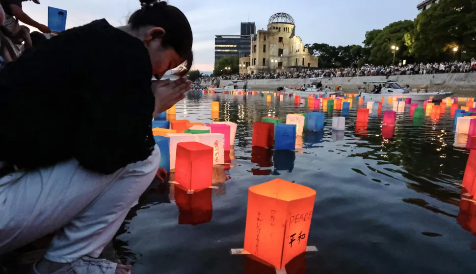 epa11529964 A woman floats a paper lantern and offers a prayer for the victims of the atomic bombing on the Motoyasu River, with the Atomic Bomb Dome (C-rear) seen in the background, in Hiroshima, western Japan, 06 August 2024. Hiroshima marks the 79th anniversary since the atomic bombing of the city on 06 August 1945, killing around 140,000 people by the end of 1945, according to Hiroshima City. EPA/JIJI PRESS JAPAN OUT EDITORIAL USE ONLY