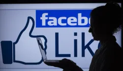 ILLUSTRATION - A woman works on her computer in front of the lighted facebook-sign in Schwerin, Germany, 04 April 2013. In Germany alone the social network counts over 25 million users. Photo: Jens Buettner/DPA/PIXSELL