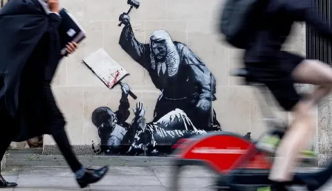 LONDON, 8. rujna 2025. (Hina/Reuters) - Britanski ulični umjetnik Bansky naslikao je mural na londonskom Visokom sudu koji prikazuje suca koji tuče prosvjednika, što je vjerojatno reakcija na uhićenje stotina prosvjednika na skupu potpore zabranjenoj skupini Akcija za Palestinu.