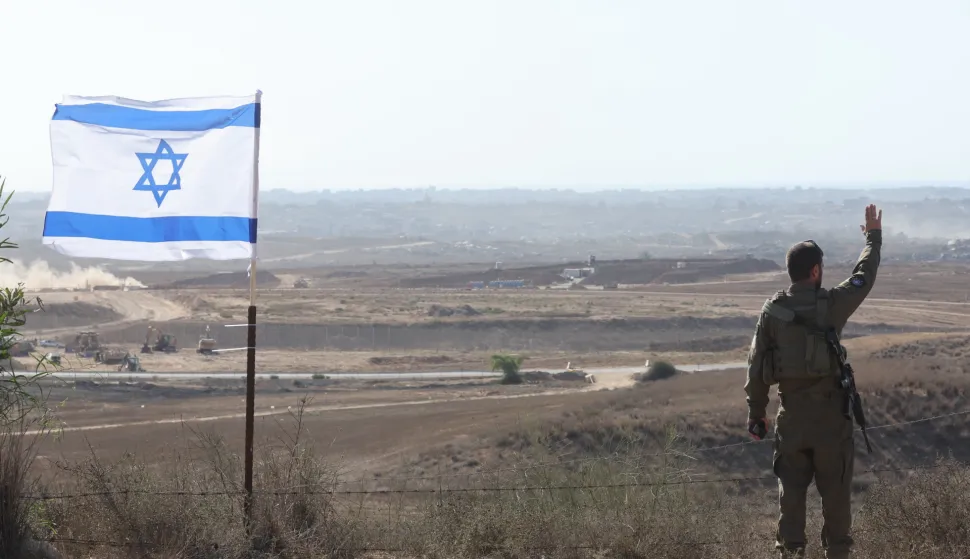 epa12272998 An Israeli soldier gestures next to an Israeli flag at an area near the Israel-Gaza border in southern Israel, 30 July 2025. EPA/ABIR SULTAN