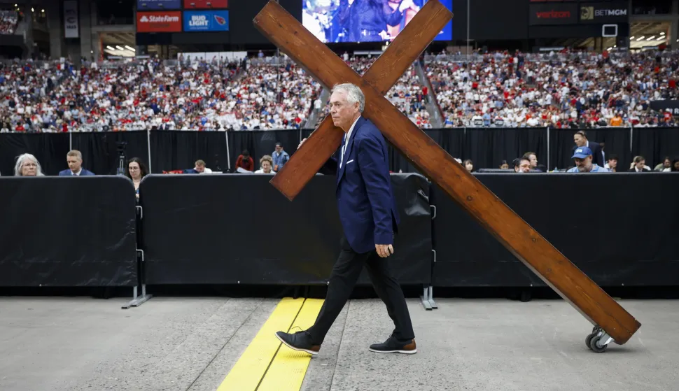 epaselect epa12396242 Dan Beasley carries a wooden cross through State Farm Stadium ahead of the public memorial service of political activist Charlie Kirk in Glendale, Arizona, USA, 21 September 2025. Kirk was shot and killed on 10 September during a stop on his American Comeback Tour organized by Turning Point USA at Utah Valley University. EPA/CAROLINE BREHMAN