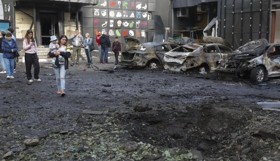 epa12072625 Locals look at a shelling hole at the site of an overnight drone strike that hit a residential area in Kyiv, Ukraine, 04 May 2025, amid the ongoing Russian invasion. At least eleven people were injured, including two children, in the strike on the residential area, according to the State Emergency Service report. Russia launched a large-scale overnight attack using 165 drones across all of Ukraine, according to the Air Force Command of Ukraine. EPA/SERGEY DOLZHENKO