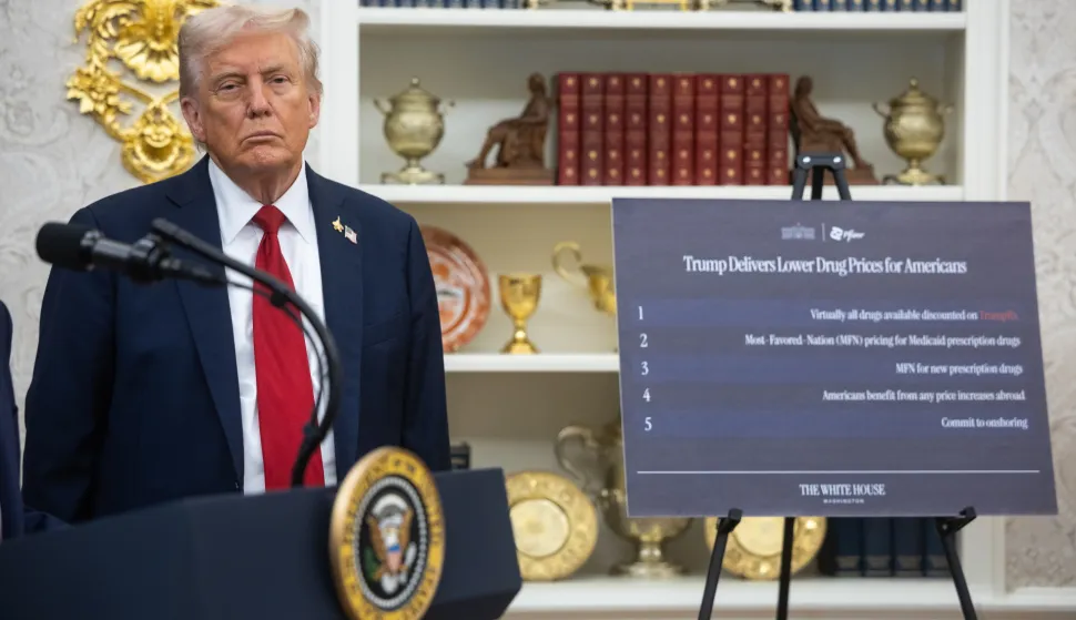 epa12417475 US President Donald Trump stands near a sign on lowering drug prices for Americans as he announces a drug-pricing deal with Pfizer in the Oval Office at the White House in Washington, DC, USA, 30 September 2025. EPA/FRANCIS CHUNG/POOL
