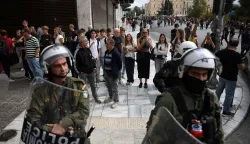 epa12452775 Tourists are pictured along with riot police officers during a demonstration of a 24-hour nationwide general strike, in Athens, Greece, 14 October 2025. The Athens Labor Center (EKA) and the Civil Servants' Confederation (ADEDY) are staging a 24-hour general strike in response to the provisions of the new labor bill being debated in Parliament, which establishes the '13-hour workday. EPA/GEORGE VITSARAS