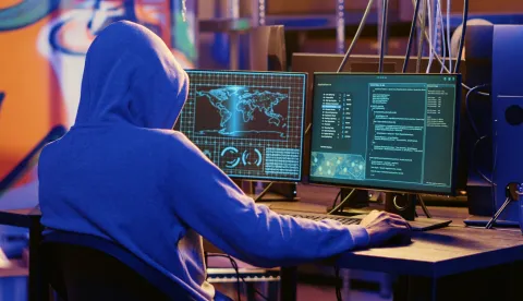 Hooded spy in underground hideout trying to steal valuable data by targeting governmental websites with weak security. Espionage specialist doing cyber attacks to gain access to sensitive inforačunalo haker prijevara kriptovalute 