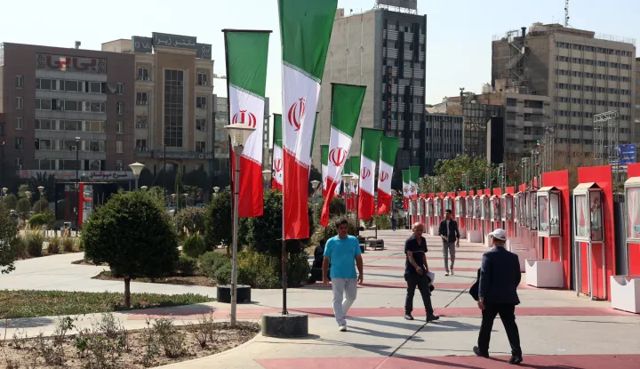 epa12466624 Iranians walk past Iran's national flags on a street in Tehran, Iran, 20 October 2025. EPA/ABEDIN TAHERKENAREH