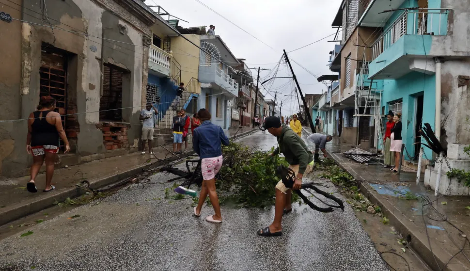 epa12490840 People clear debris on a street affected by Hurricane Melissa in Santiago de Cuba, Cuba, 29 October 2025. Melissa is moving away from Cuba as a Category 2 hurricane, with maximum sustained winds of up to 160 kilometers per hour, and is beginning to head toward the Bahamas after causing flooding, river overflows, and landslides in eastern Cuba. EPA/Ernesto Mastrascusa