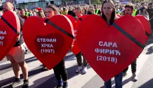 epa12496902 The names of the victims are displayed on oversized heart cut-outs as people observe 16 minutes of silences as they pay respect to the victims in front of the Novi Sad train station during the commemoration in Novi Sad, Serbia, 01 November 2025. The student-led event marks the first anniversary of the railway station canopy collapse that killed 16 people, sparking widespread protests demanding political accountability. EPA/ANDREJ CUKIC