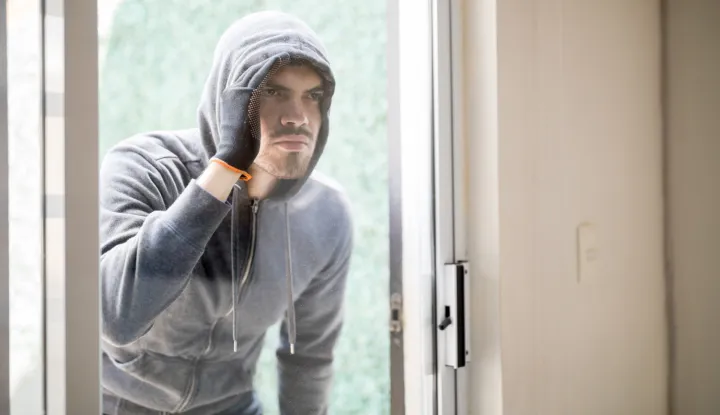 Portrait of a male robber wearing a hoodie and gloves looking inside a house through a glass doorlopov kradljivac provala kuća sigurnost kriminal krađa ilustracija freepik