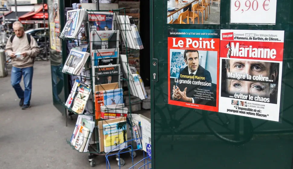 epa09907965 A man walks next to a kiosk showing French newspapers with pictures of French President Emmanuel Macron, in Paris, France, 25 April 2022. Emmanuel Macron defeated Marine Le Pen in the final round of France's presidential election on 24 April, with exit polls indicating that Macron led with approximately 58 percent of the vote. EPA/Mohammed Badra