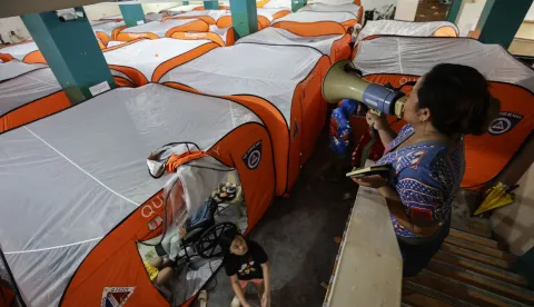 epa12513651 A village assistance personnel makes an announcement at an evacuation center set up in anticipation of Typhoon Fung-Wong in Quezon City, Metro Manila, Philippines, 09 November 2025. According to the Philippine Atmospheric, Geophysical, and Astronomical Services Administration (PAGASA), the typhoon is projected to be 100 kilometers northeast of Daet, Camarines Norte in the Bicol region, moving west-northwest at 30 kilometers per hour with maximum winds of 185 kilometers per hour. EPA/ROLEX DELA PENA