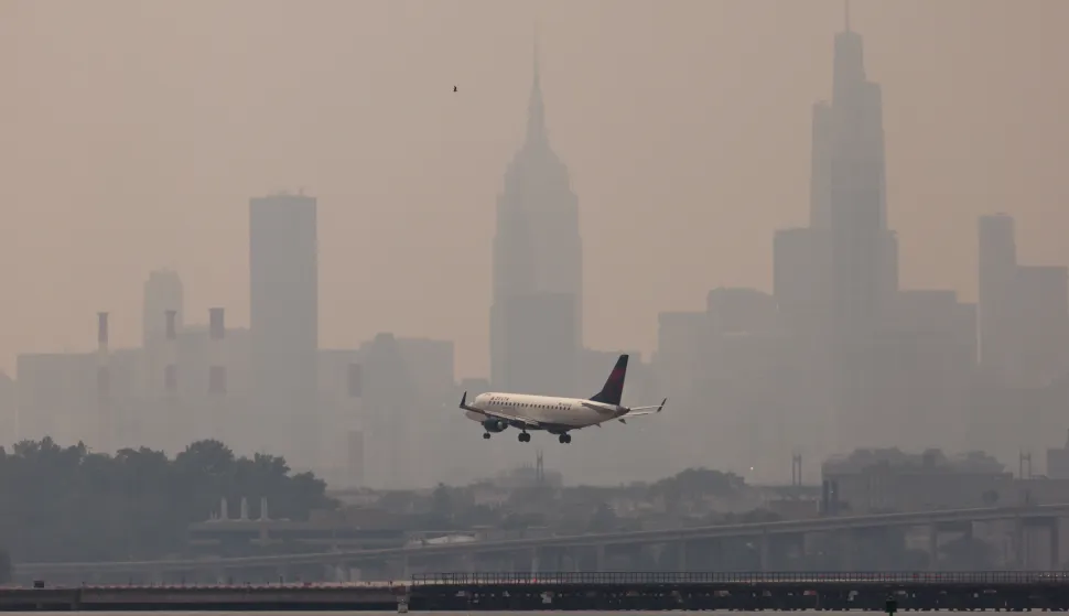 epa10680359 An airplane lands at LaGuardia airport with buildings in Manhattan skyline in the background as smoke from wildfires burning in Canada continues to create unhealthy air quality conditions in New York, New York, USA, 08 June 2023. New York City continues to be under an air quality alert as result of the smoke, which is affecting large portions of the United States and causing flight delays around as well as ground stops due to poor visibility. EPA/JUSTIN LANE