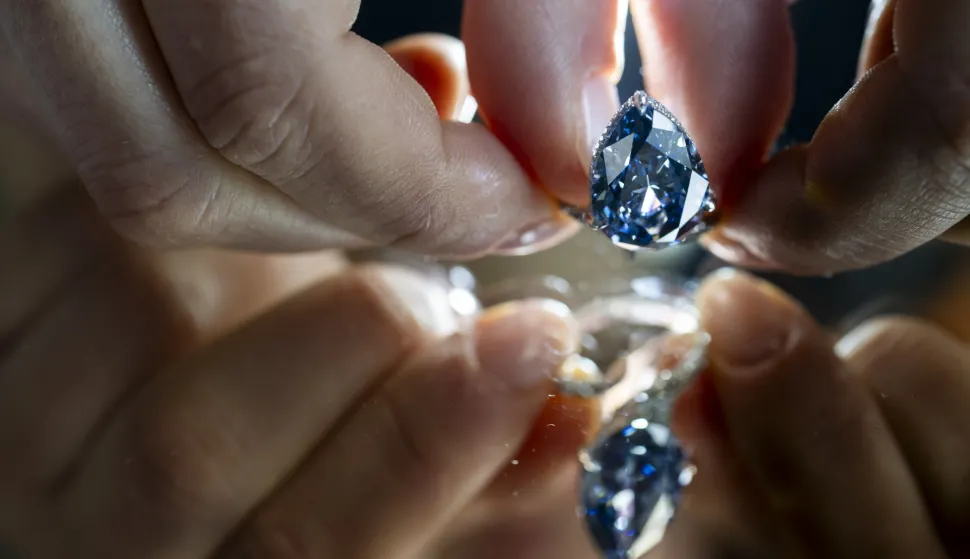 epa12510130 A Christie's employee displays the Mellon Blue, a fancy Vivid Blue pear-shaped cut diamond of 9.51 carats, during a preview at the Christie's auction house in Geneva, Switzerland, 07 November 2025. The piece will be auctioned in Geneva on 11 November 2025. EPA/MARTIAL TREZZINI
