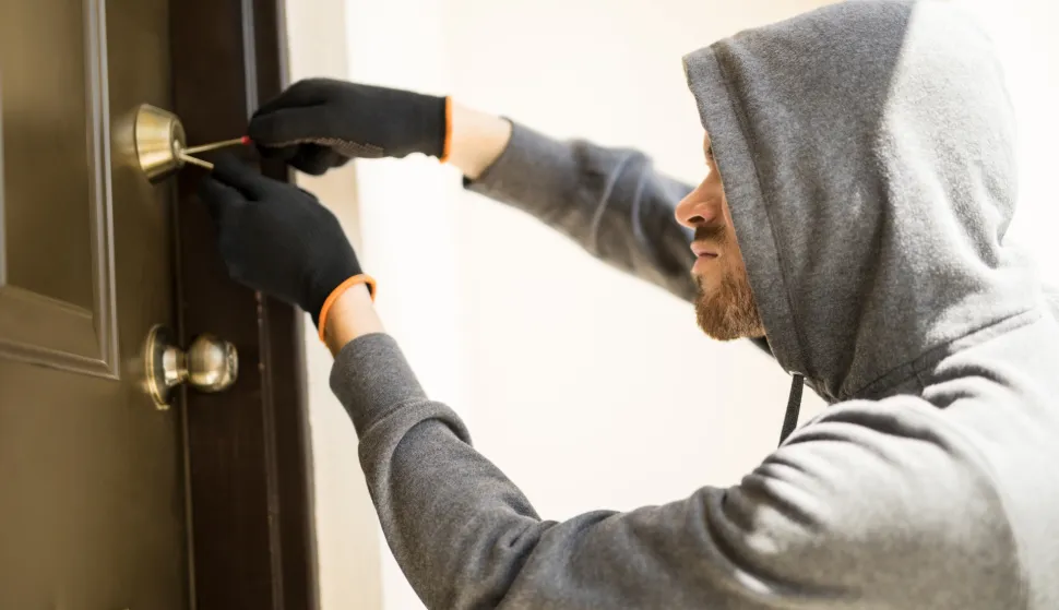 Profile view of a man with a hoodie trying to pick a lock in a house and forcing his entrylopov kradja provala krađa kradljivac kriminal provalnik obijanje brave ilustracija freepik
