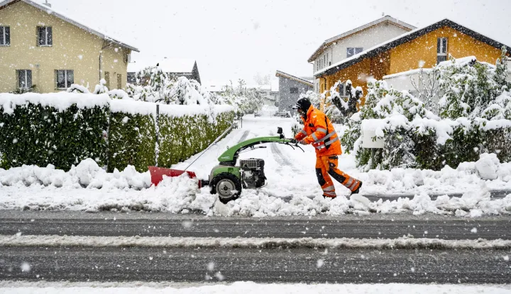 epa12036356 A municipal employee removes snow from a road with a machine in Saillon, Canton Valais, Switzerland, 17 April 2025. Storms brought flooding, landslides, heavy snow, and fallen trees to Valais, severely disrupting traffic. Numerous rail and road links were closed, with the Brig region hit particularly hard. EPA/JEAN-CHRISTOPHE BOTT
