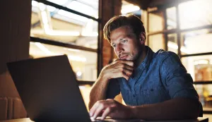 Laptop, thinking and business man reading email for project, research and deadline at night. Computer, creative and web designer problem solving or planning solution for software update in startup