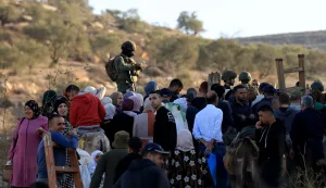epa12541406 Israeli soldiers on guard as Palestinian farmers make their way to pass a gate giving them access to their olive feild close to the Alon More settelment near the West Bank village of Salem, near the West Bank city of Nablus, 22 November 2025. Farmers across the West Bank have faced repeated attacks by Israeli settlers and soldiers during the olive harvest season, in assaults often including physical violence, harassment, uprooting of trees, and blocking access to agricultural lands located near or within settlement areas. EPA/ALAA BADARNEH