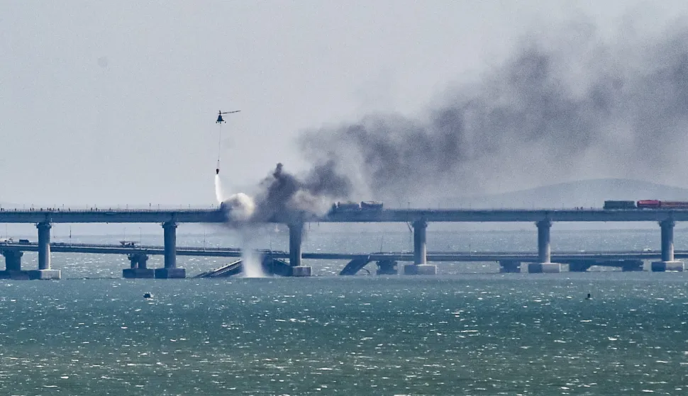 epa10230633 A firefighter helicopter pours water on fire on a collapsed part of the Kerch Strait bridge in Crimea, 08 October 2022. According to Russian authorities, "an explosion was set off at a cargo vehicle on the motorway part of the Crimean bridge on the side of the Taman peninsula, which set fire to seven fuel tanks of a train that was en route to the Crimean peninsula. Two motorway sections of the bridge partially collapsed." EPA/STRINGER