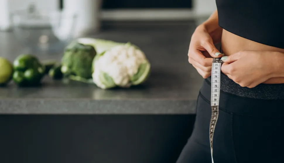 Young woman with measuting tape on weist at the kitchenmrsavljenje debljina vjezba freepik