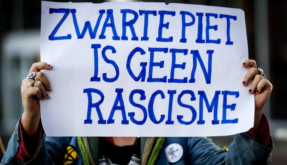 epa07078466 A sympathizer of the traditional figure Black Pete display a placard reading, 'Zwarte Piet is not racism', outside the court in Leeuwarden, Netherlands, 08 October 2018. Some 34 people suspected of blocking a road on the day of the national Sinterklaas race in 2017, had to appear in court. Black Pete or Zwarte Piet is the companion of Saint Nicolas during the Sinterklaas (Saint Nicolas) festival celebrated on the evening of 05 December, and has become the subject of much controversy in recent years as some people think it is racist. EPA/ROBIN OF LONKHUIJSEN