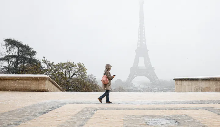 epa11733282 A woman walks during snowfall near the Eiffel Tower in Paris, France, 21 November 2024. French National Weather and Climate Service Meteo-France issued an 'orange' warning in 32 departments from northern Brittany and Normandy to the Ile-de-France due to snowfall and freezing rain forecasted on 21 November. EPA/MOHAMMED BADRA