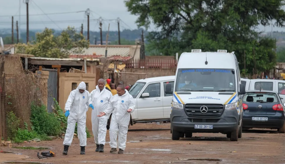 South African Police Service (SAPS) Forensic Pathology Services members gesture at the scene of an attack at a tavern in Bekkersdal on December 21, 2025. Nine people were killed when gunmen opened fire at a bar outside Johannesburg early on December 21, 2025.Ten more were wounded in the early morning attack at the tavern at Bekkersdal, in a gold mining area around 40 kilometres (25 miles) southwest of the city. (Photo by EMMANUEL CROSET/AFP)